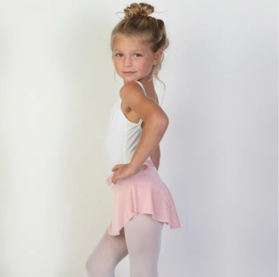 A young ballerina wears a soft, light pink flowy Bullet Pointe ballet skirt.