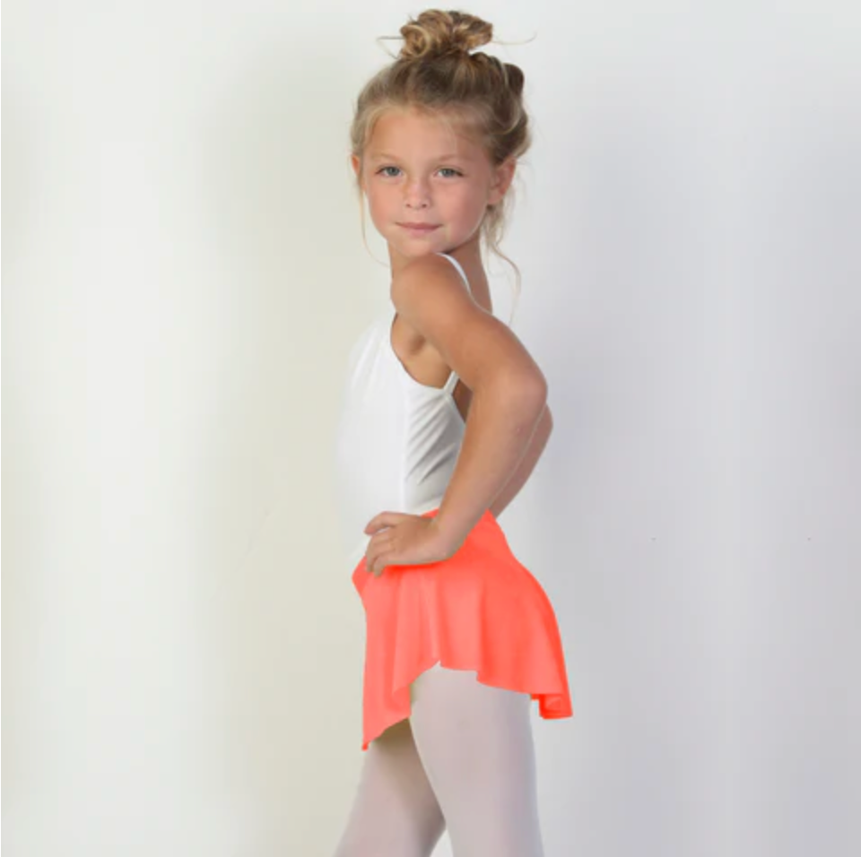 A young ballerina wears a bright coral flowy Bullet Pointe ballet skirt.
