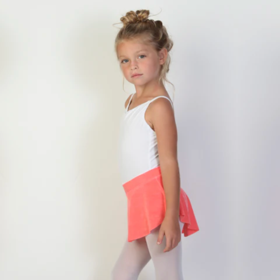 A young ballerina wears a bright coral flowy Bullet Pointe ballet skirt.