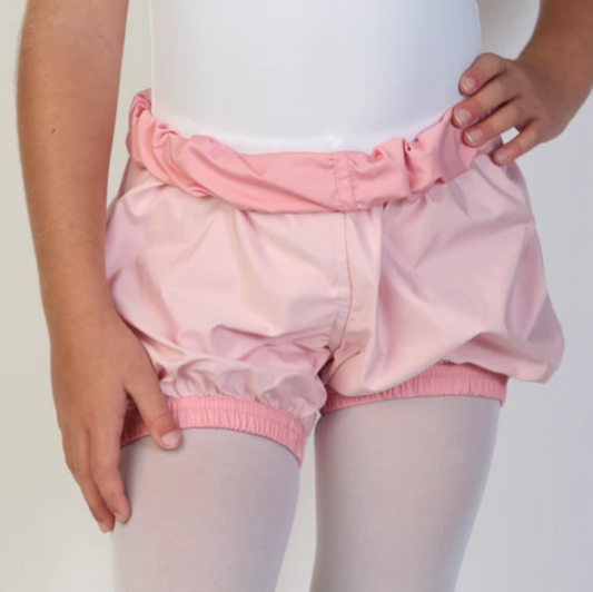 A young ballerina wears light pink trash-bag style shorts with a bubblegum pink waistband.