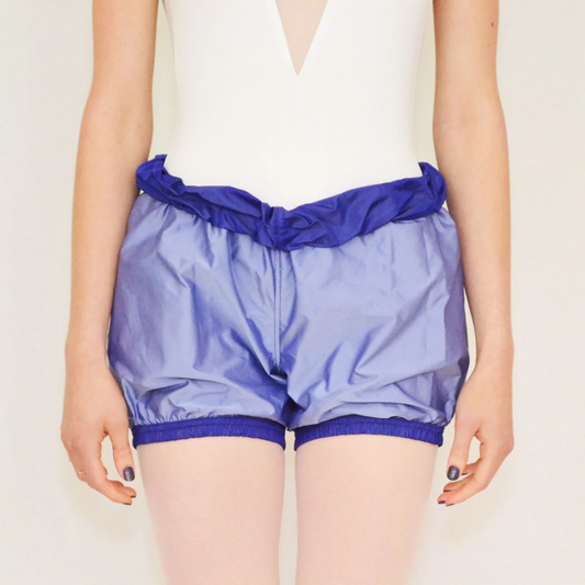 A dancer wears lilac trash-bag style shorts with a royal purple waistband.